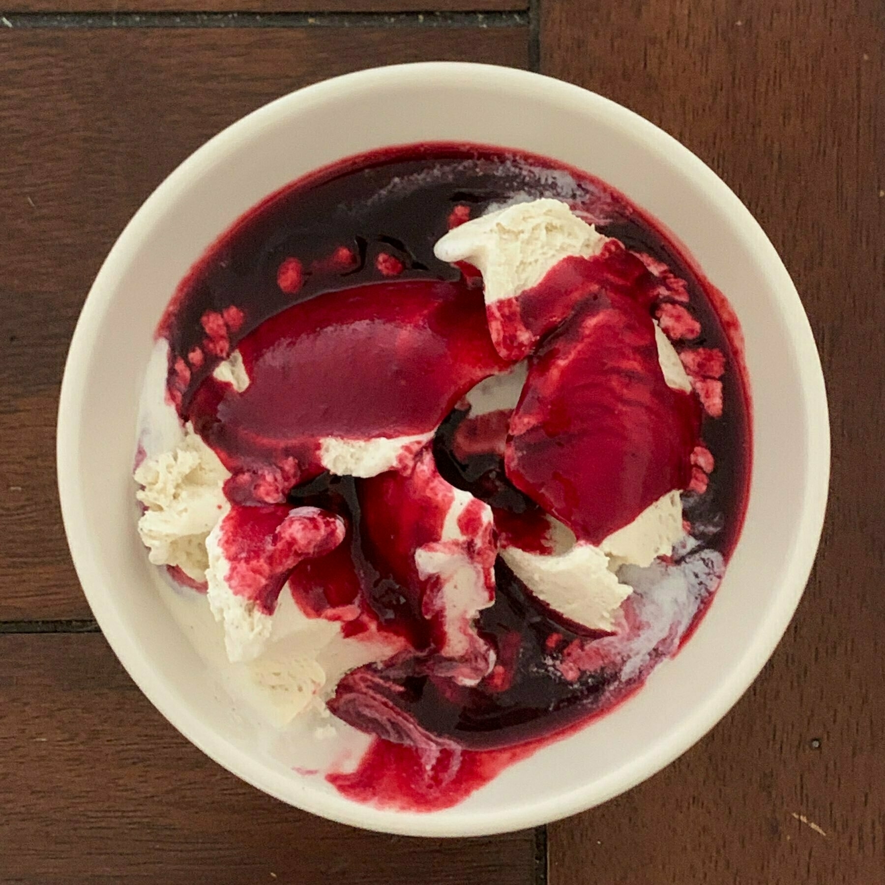 top down view of a bowl of vanilla ice cream with blackberry sauce